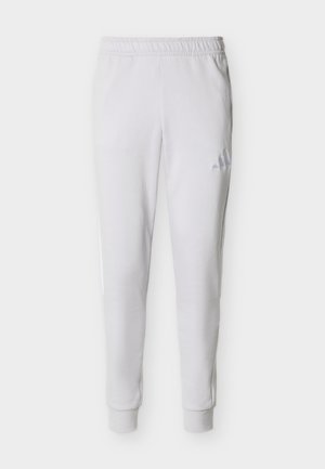 Λευκό αθλητικό παντελόνι jogging με ελαστική μέση, αστραγάλους με μανσέτα και διακριτικό λογότυπο Adidas στο πάνω μέρος του αριστερού μηρού.