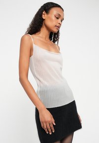 Lett, ribbestrikket topp i gradientnyanser av myk grå og hvit, med tynne stropper og en tettsittende silhuett.