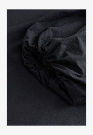 Tessuto nero con una texture liscia e un bordo arricciato ed elasticizzato, che mostra una sottile lucentezza e motivi intrecciati fini.