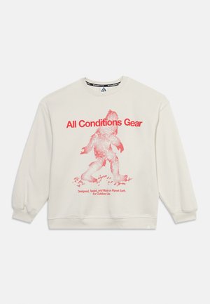 Sweat-shirt blanc à manches longues col rond avec texte rouge "All Conditions Gear" et une silhouette rouge pixellisée en train de marcher, plus un texte plus petit en bas.