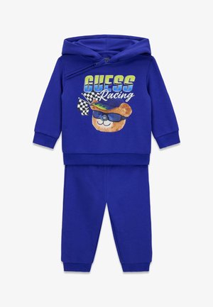 Blauer Baumwoll-Trainingsanzug mit einem Kapuzenpullover, der eine Grafik eines Bären, Sonnenbrillen und Rennflaggen zeigt; dazu passende Hosen.