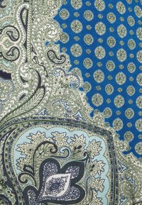 Tissu à fond bleu présentant des motifs complexes de paisley et géométriques en nuances de vert et de crème, montrant des détails fins et des textures.