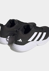 Black athletic shoes featuring a mesh upper, white three-stripe design, and a cushioned sole with traction pattern for grip.