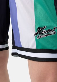 Șorturi sportive multicolore din material mesh, cu dungi violete, verzi, negre și albe. Include logo-ul brodat "Kani" pe tiv.