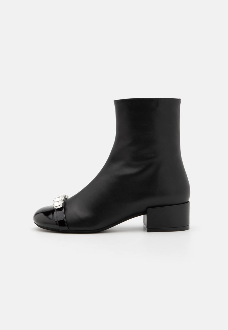 Black leather ankle boots with a smooth finish, round toe, small block heel, and decorative silver hardware on the toe cap.