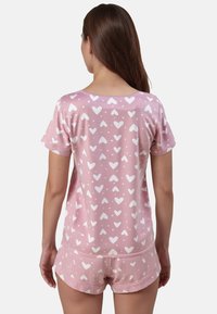 Set di pigiama corto rosa composto da una maglietta a maniche corte e pantaloni corti con motivi di cuori e pois bianchi, realizzato in un tessuto liscio e leggero.