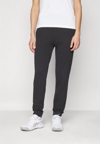 Grå joggebukser med slim fit, elastisk midje og manchetter på anklene. Kombinert med hvite joggesko og en enkel hvit t-skjorte.