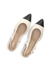Beige leren schoenen met spitse neuzen en een zwarte punt, met uitgesneden zijkanten en een gespband, een gladde textuur en een beige binnenzool.