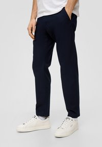 Granatowe spodnie zwężane z teksturowanej tkaniny, wyposażone w kieszenie boczne i połączone z białymi sneakersami, prezentujące elegancki design i czyste linie.