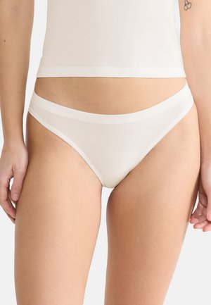 Witte naadloze string met een zachte, elastische tailleband. Glad materiaal, minimalistisch ontwerp en een subtiele glanstextuur.
