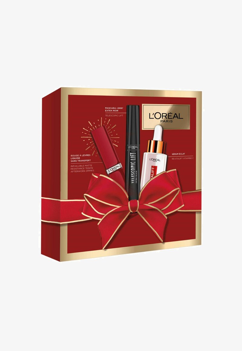 Boîte-cadeau rouge avec des accents dorés et un grand nœud rouge, contenant des produits de maquillage L'Oréal Paris : mascara, rouge à lèvres liquide et sérum.