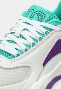 Biała sportowa buty z turkusową siateczkową cholewką, białymi sznurówkami i fioletowymi akcentami po bokach. Logo TYR na języku. Teksturowany wzór.