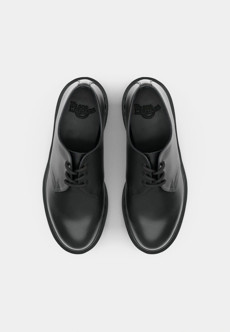 Scarpe in pelle nera con una finitura liscia, punta arrotondata, design con lacci e branding minimalista sulle solette. Suole in gomma piatte.