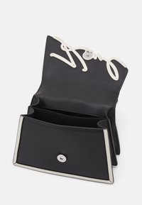 Czarny skórzany portfel z białym logo na górze, posiadający dwa sloty na karty i metalowe zapięcie, gładka faktura, minimalistyczny design.