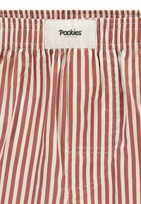 Shorts din material în dungi roșii și crem, cu un brâu elastic și o mică buzunar. Eticheta de la brâu spune "Pockies."