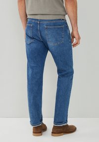 Jeans de mezclilla azul con corte recto, que presentan dos bolsillos traseros y costuras visibles. Con dobladillos acampanados y una textura suave.