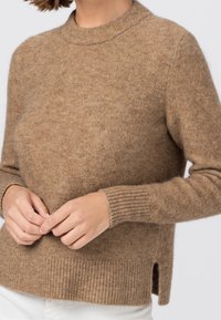 Suéter de lana marrón con cuello redondo, puños y dobladillo acanalados, con aberturas laterales. Textura suave con un tono cálido y sutil.