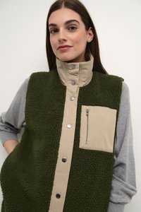 Vest din polar verde cu accente bej, guler înalt, nasturi cu clips pe față și un buzunar cu fermoar pe pieptul stâng. Suprafață texturată.