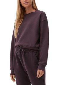 Felpa viola con scollo tondo, maniche lunghe e polsini a costine, abbinata a pantaloni della tuta coordinati con vita regolabile a coulisse.