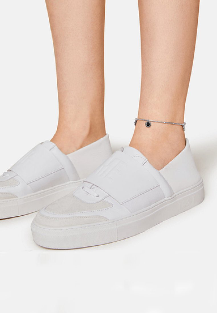 Weiße Slipsneaker aus einer Mischung aus glatten und strukturierten Materialien. Sie verfügen über eine weiche Wildlederfront, eine dicke Sohle und ein Logo am Riemen.