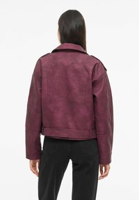 Pruunikas kunstnahast jakk õlapaeltega, laia krae, soonilise tekstuuriga detailide ja reguleeritava vööosaga, nähtud tagantpoolt.