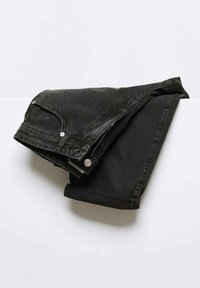Jean en denim noir plié reposant sur une surface blanche avec détails visibles de poche avant, bouton et fermeture éclair.