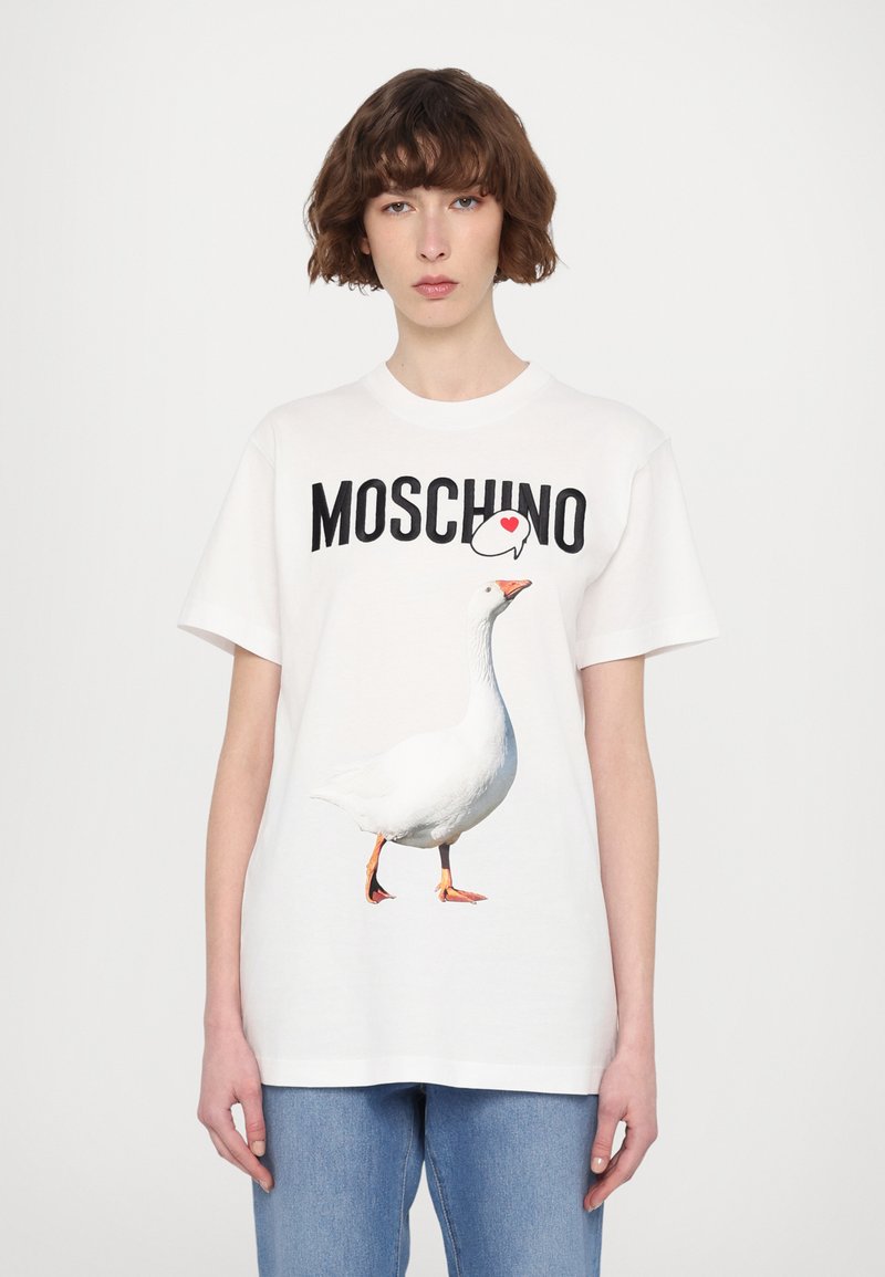 Balta medvilninė marška su dideliu piešiniu, kuriame matomas žygiuojantis žąsys, o viršuje užrašas "MOSCHINO" juoda spalva. Neformalus dizainas, trumpomis rankovėmis.