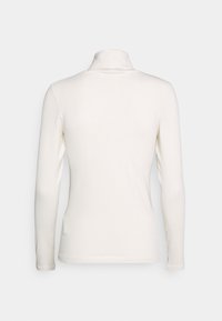 Långärmad polokrage topp i off-white, med en figurnära design och slät textur, samt ett subtilt ribbat mönster längs tyget.