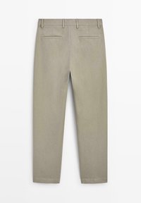 Beige byxor med raka ben, hällor för bälte och två bakfickor med kant, visade platt bakifrån.