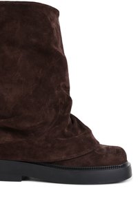 Botte mi-mollet en daim marron foncé avec un design supérieur souple et une semelle épaisse en caoutchouc noir.