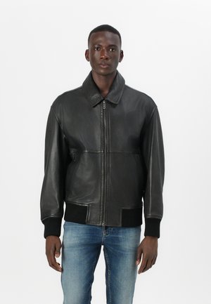 Veste bomber en cuir noir avec un col, fermeture éclair, poignets et ourlet côtelés. Texture lisse sans motifs ni accents visibles.