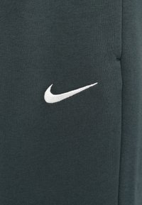Hall hall Nike'i sweatshirt, millel on pehme tekstuur. Rinnal on valge tikandiga logo. Lihtne disain, ilma mustriteta.