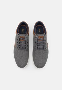 Sneaker in tessuto grigio con accenti in pelle marrone, punta rotonda e suola bianca. Presentano chiusura con lacci e fodera in tessuto.