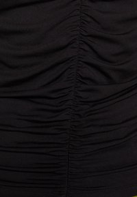 Tessuto elasticizzato nero con dettagli arricciati verticali. Texture morbida e finitura liscia, che mette in risalto le sezioni arricciate lungo i lati.