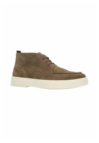 Bruine suede chukka boot met een witte zool, met een ronde neus, gestikte details en een groene lus aan de achterkant.