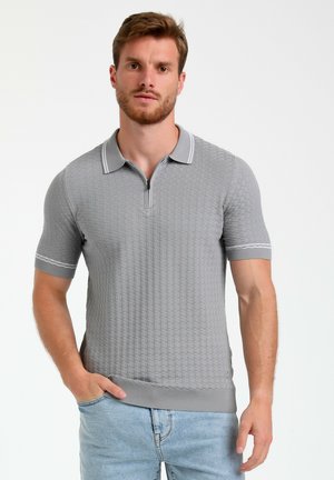 Gray textured polo shirt with short sleeves, zipper placket, and contrast trim on the collar and sleeves. Worn with light blue jeans.