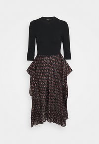 Czarna bluzka z rękawami Three-Quarter, połączona z zwiewną spódnicą w ciemnych tonach, z czerwonymi i białymi abstrakcyjnymi kształtami oraz falbanami.