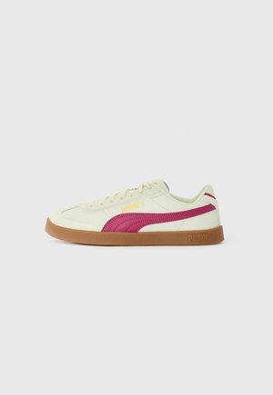 Lys grønne sneakers med en pink stribe, der har en gummisål og et iøjnefaldende Puma-logo i gul. Glat lædertekstur og rund form.