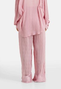 Lichtroze plissé top en bijpassende broek met een zachte, textuurafwerking. De losse pasvorm en vloeiende ontwerp vergroten het comfort en het bewegingsgemak.