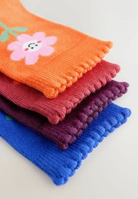 Quatre paires de jambières tricotées en orange avec une fleur rose, bordeaux, violet foncé et bleu. Tissu texturé avec bordure côtelée.