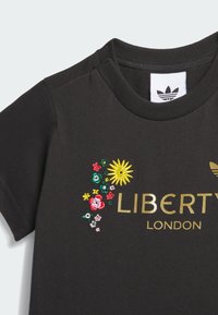 Μαύρο βαμβακερό T-shirt με πολύχρωμη κεντητή ανθοδέσμη και χρυσά γράμματα "LIBERTY LONDON", με ριμπ λαιμόκοψη και κοντά μανίκια.