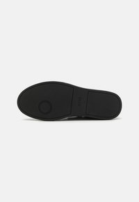 Semelle de chaussure en caoutchouc noir avec une texture antidérapante, un accent circulaire, une finition lisse, et sans aucune marque visible à part le mot 'BOSS' en relief.