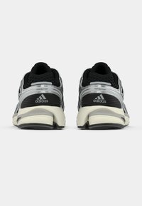 Mustad ja hõbedased tossud võrgust pealmise osaga, polsterdatud kaelusega, ikoonilise kolme triibu logoga ja tekstuurse tallaga. Omavad FORMOTIONi brändingut.