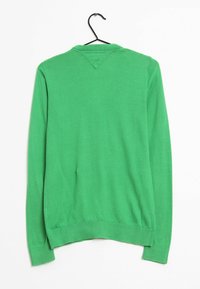 Zelený svetr s dlouhými rukávy, ve výstřihu do V a s žebrovanými manžetami. Hladký povrch, vyrobený z lehkého materiálu, zavěšený na černém ramínku.