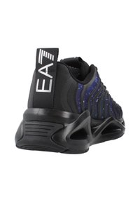 Scarpe da atletica nere con un design ondulato e testurizzato che presenta un gradiente blu e viola. Suola nera spessa con scanalature evidenti e caviglia imbottita.