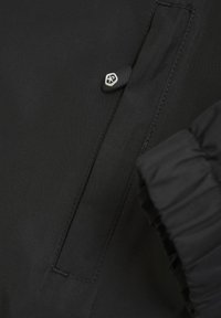 Svart vattentät jacka med en slät textur, med en blixtlåsficka och detaljerade skräddade manschetter för en snug passform. Minimalistiska designelement.