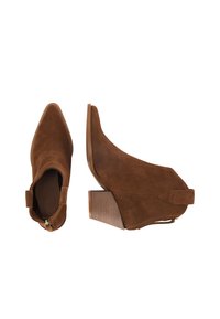 Stivali ankle in suede marrone con punta affusolata, cerniera laterale e tacco in legno impilato. Il design presenta una texture liscia e accenti minimi.
