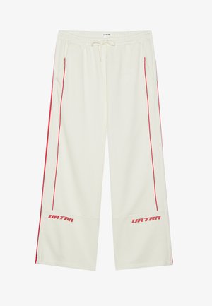 Krém színű melegítőnadrág piros oldalsávokkal, rugalmas derékkal, húzózsinórral és "URTRN" logóval a bal alsó lábszáron. Puha tapintás.