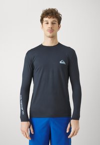 Dlhý rukáv, priliehavý čierny rash guard vyrobený z elastického materiálu, s svetlomodrým logom na hrudi a bielym textom na rukáve.