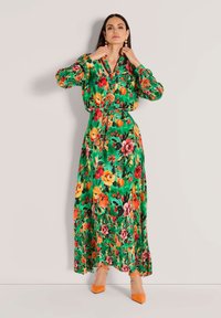 Floral Maxi-Kleid aus grünem Stoff mit bunten Blumen, langen Ärmeln, Knopfdetails, einem Taillen-Zugband und einem fließenden Saum.